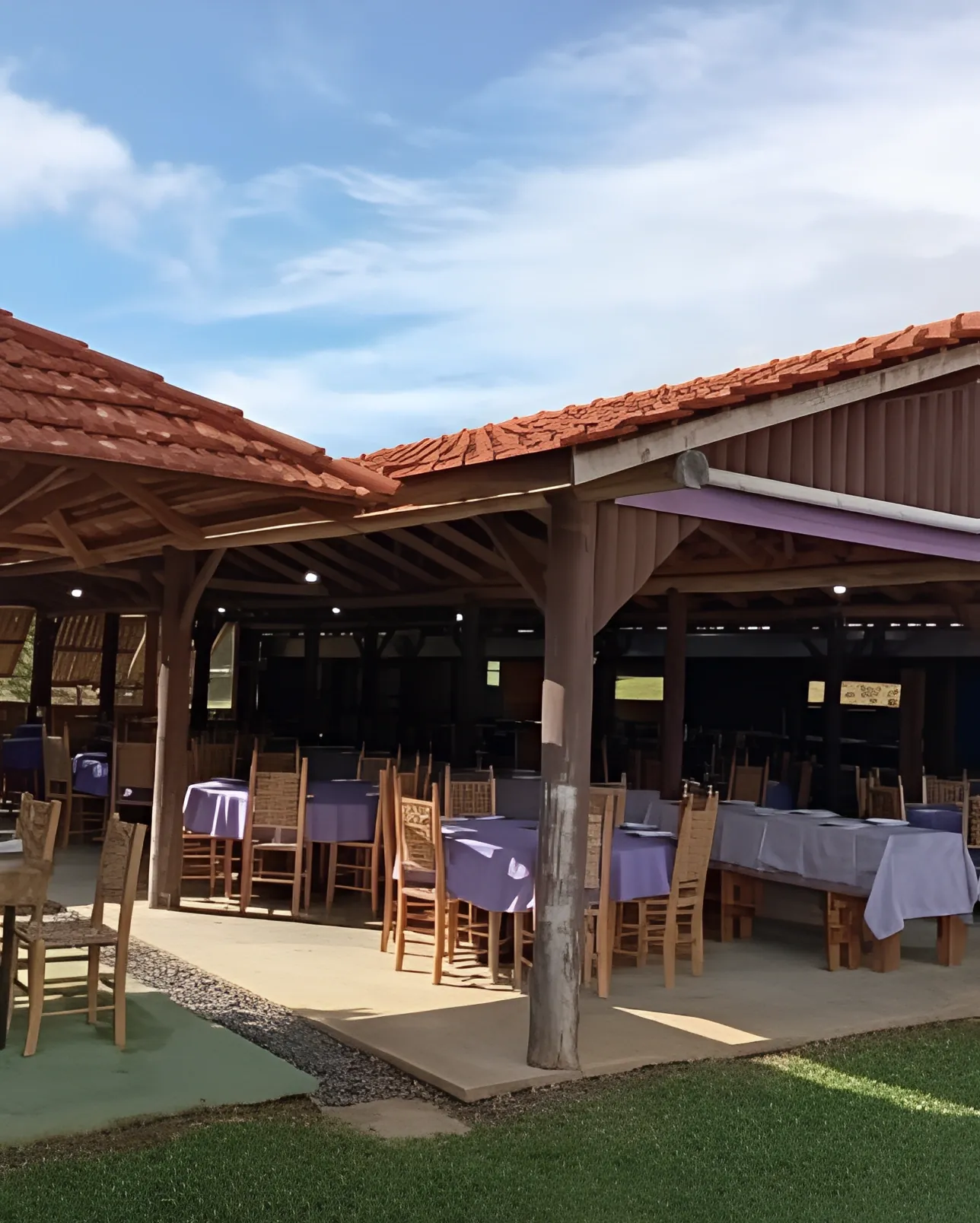 Restaurante com mesas de toalha lilás cercado de gramado